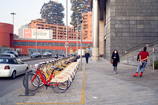 Bicycle rental service stand in row parking on Garibaldi area. Bicycles with basket for traveling around Milan waiting cyclists. Public street transportation. Milan, Italy - July 20, 2020