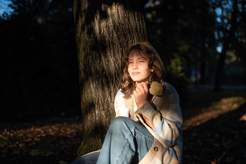 Portrait of a teenage girl reading a book in a city park