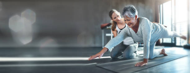 Working together to improve muscle strength and tone ejercicio, maqueta y mujer madura en el gimnasio con entrenamiento de entrenador personal, ayuda y estiramiento en la pancarta. espacio de información, fitness y persona mayor con reto de fisioterapia en el suelo, motivación de entrenamiento y bokeh