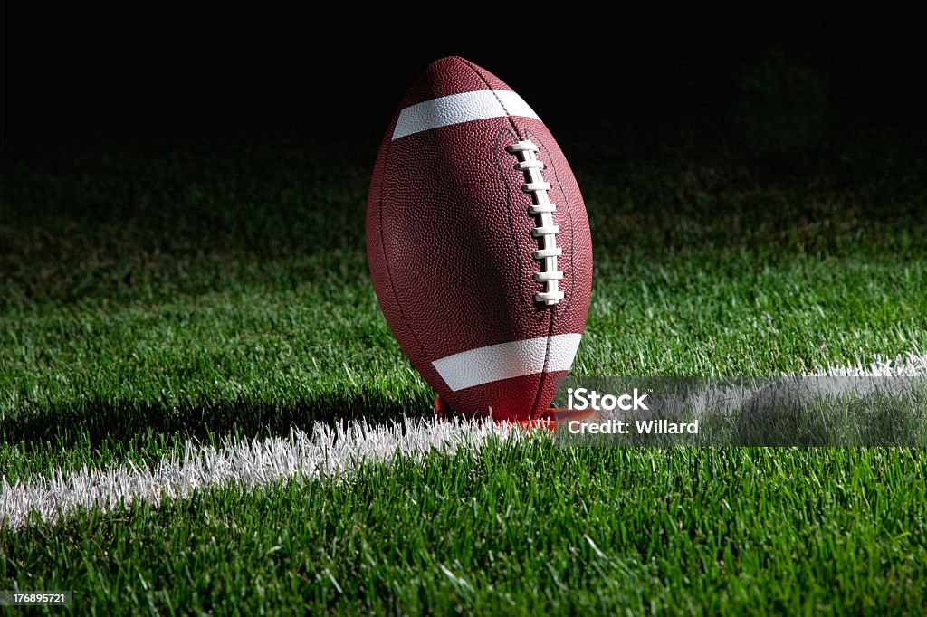 American football standing on tee at night College football on tee on yard line ready for kickoffOther football images: American Football - Sport Stock Photo