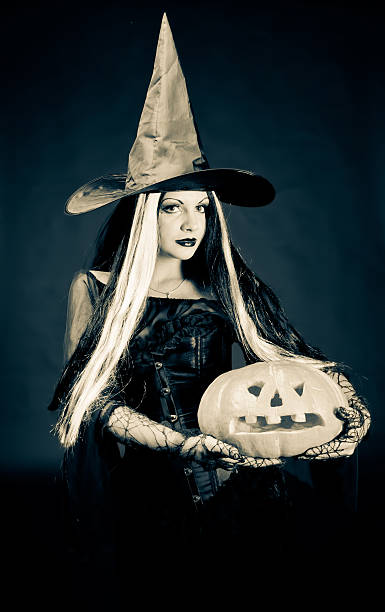 istock Halloween witch withcarved pumpkin over dark background 176895966