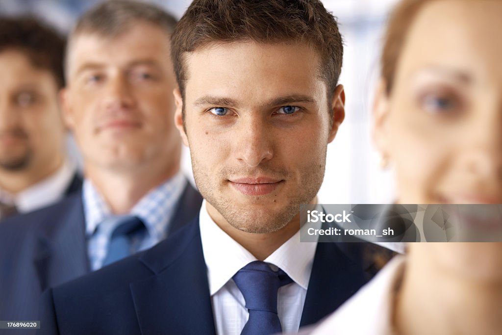 Closeup of Businessman With Colleagues. Closeup portrait of a young businessman standing in the row with his colleagues. Achievement Stock Photo