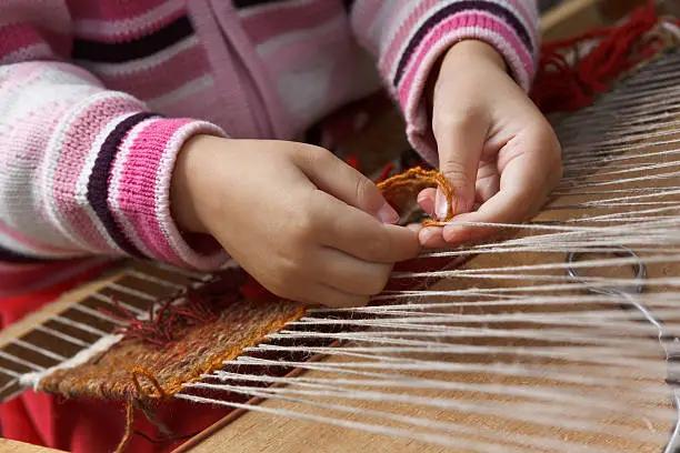 The child learns to weave a tapestry.
