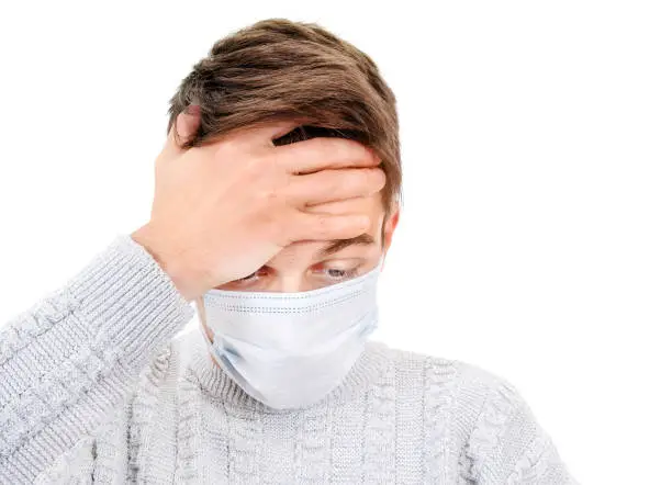 Sick Young Man in a Surgical Mask feel Headache Isolated on the White Background closeup