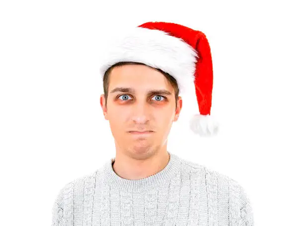 Unhappy Young Man in Santa Hat with Bruises under his Eyes Isolated on the White Background closeup