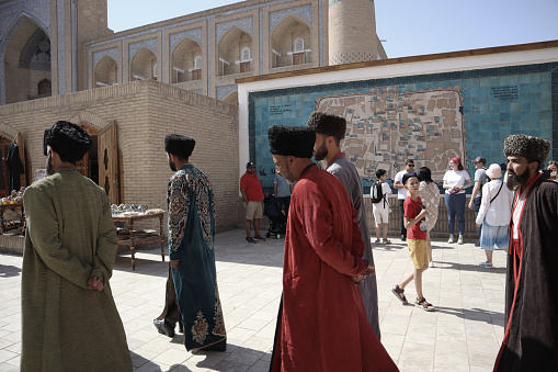 Streets of the old city of Khiva. A group of men in national costumes. 2.05.2023. Khiva, Uzbekistan.
