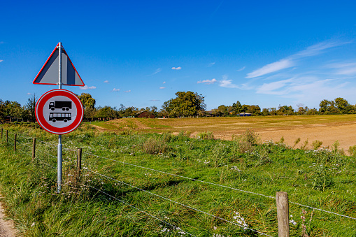 Dutch agricultural landscape with a traffic sign: no trucks and buses, next to a rural road, agricultural plots, farms and trees against blue sky in background, sunny day in Meers, Elsloo, Netherlands