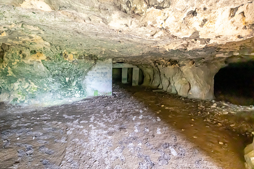 Interior of an empty cave, walls with uneven texture and cracks, concrete supports or columns in background, Thier de Lanaye nature reserve in Belgian part of Sint-Pietersberg in Vise, Belgium