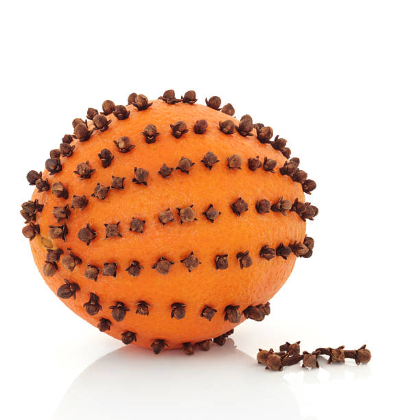 Orange and Clove Pomander "Orange pomander fruit studded with clove spice, and scattered, isolated over white background." scent container stock pictures, royalty-free photos & images