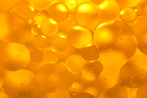 Picture of oil on the surface of the water, golden color, similar to serum for skin care.