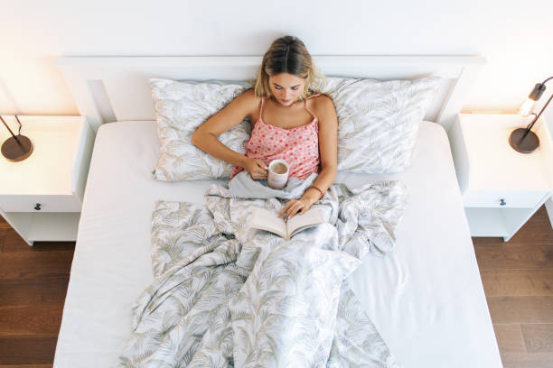 istock Young woman reading book on bed at home 1768990638