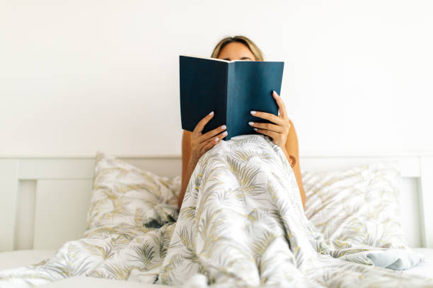 istock Young woman reading book on bed at home 1768991231