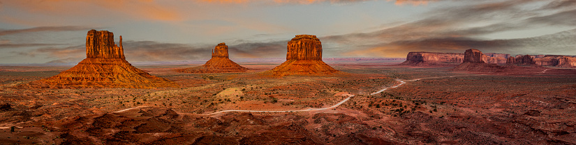 Monument Valley, on the Arizona - Utah border, gives us some of the most iconic and enduring images of the American Southwest.  The harsh empty desert is punctuated by many colorful sandstone rock formations.  It can be a photographer's dream to capture the ever-changing play of light on the buttes and mesas.  Even to the first-time visitor, Monument Valley will probably seem very familiar.  This rugged landscape has achieved fame in the movies, advertising and brochures.  It has been filmed and photographed countless times over the years.  If a movie producer was looking for a landscape that epitomizes the Old West, a better location could not be found.  This picture of the Monument Valley rock formations at sunset was photographed from John Wayne Point near the Monument Valley Visitor Center north of Kayenta, Arizona, USA.