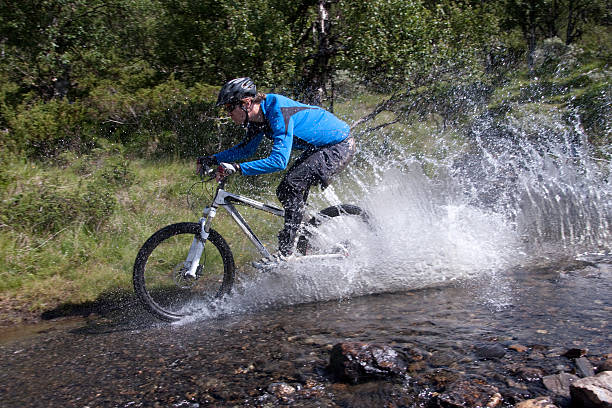 young man riding his mountain bike through a dirty puddle