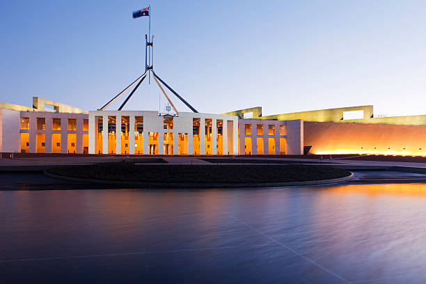 Canberra Australia Parliament House Twilight "Parliament House, Canberra, Australia, illuminated at twilight. Reflections in pool, Australian flag is flying.  For MANY MORE Australian images, please click" canberra stock pictures, royalty-free photos & images