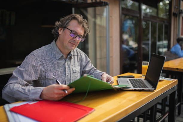 istock Mature middle-aged man is working on his laptop and writing on his documents. 1769002551