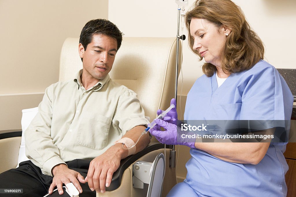 Nurse Giving Patient Injection Through Tube Female Nurse Giving Male Patient Injection Through Tube IV Drip Stock Photo