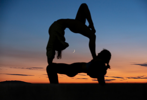 Flexible young woman's are exercising at sunset.