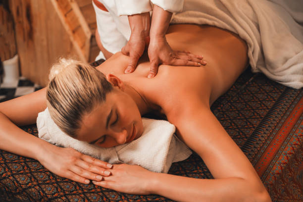 Attractive caucasian woman having back massage at warm sauna room. Tranquility. Beautiful caucasian woman having back massage in front of wooden sauna cabinet. Attractive woman feel deep in relaxation surrounded by aroma and essential oil. Relaxing and calm concept. Tranquility. swedish sauna stock pictures, royalty-free photos & images