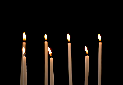 Group of Lit Church Candles on Black Background. Shot in Paris.