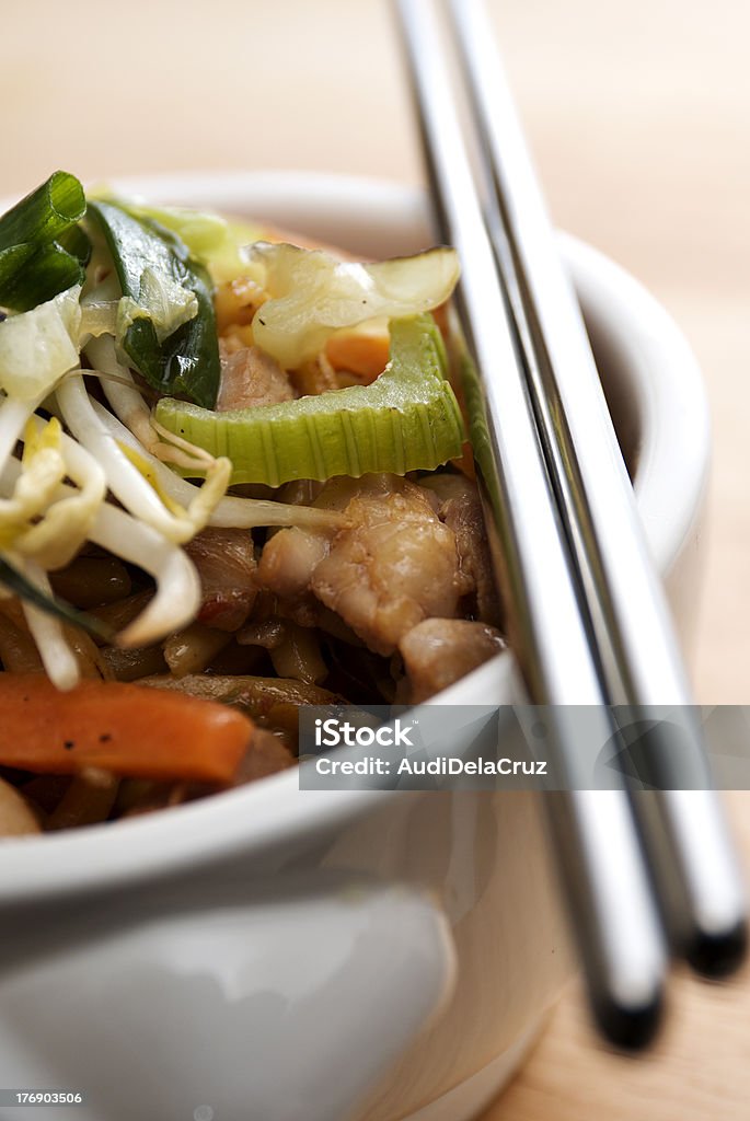 Stir Fried Chicken Noodles "close up shot of a bowl of asian stir fried noodles with chicken, celery, carrots, and bean sprouts on a wooden surface" Asian Culture Stock Photo