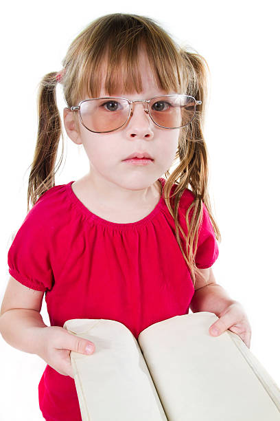 Menina cansada com o livro e vestindo espetáculos - foto de acervo