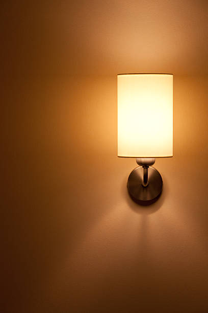 Single lit wall lamp glowing on an amber wall