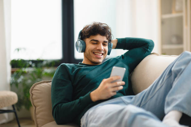 istock Guy Using Smartphone Wearing Headphones Lying On Sofa At Home 1769051516