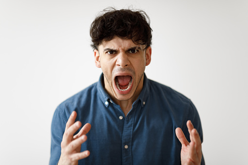Aggression. Portrait Of Angry Middle Eastern Man Shouting Loudly Expressing Negative Emotions Looking At Camera Posing Over White Studio Background. Mad Guy Yelling At You. Mental Health Problems