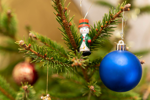 Christmas tree toys on the branches of the Christmas tree. A miniature toy and a blue ball. The concept of celebrating the New Year