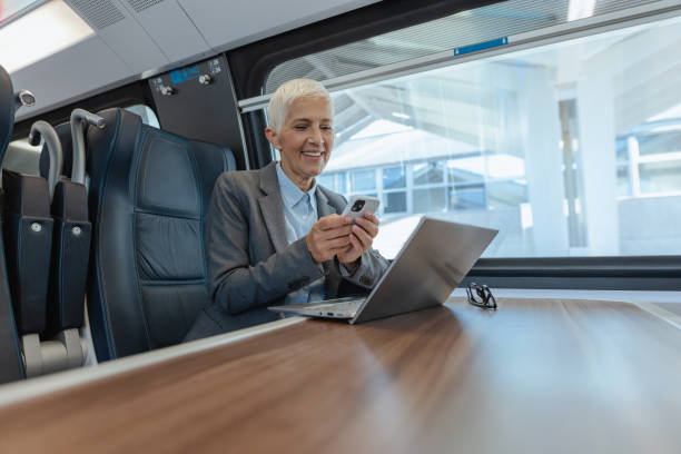 istock Senior woman working on laptop and using smart phone in the train 1769065719