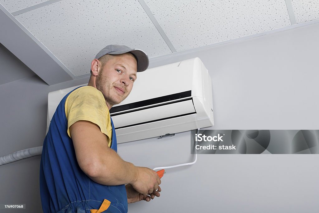 Installer sets a new air conditioner Young setup man installs the new air conditioner in the office. Air Conditioner Stock Photo