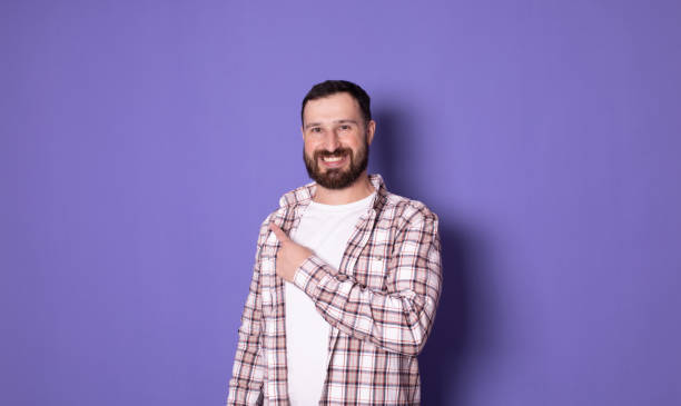 istock Handsome bearded positive cheerful man pointing with finger aside. Copyspase. 1769084419