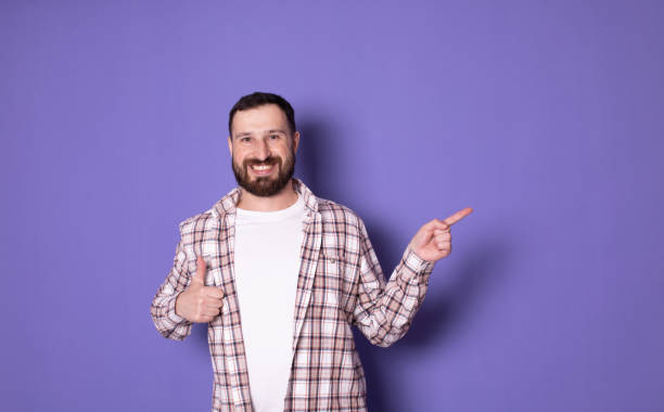 istock Handsome bearded positive cheerful man pointing with finger aside. Copyspase. 1769084427