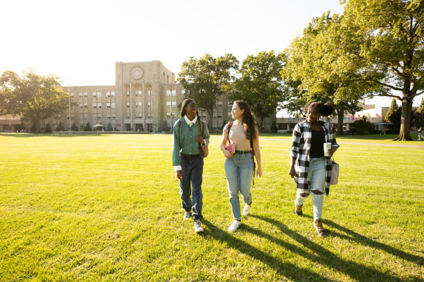 Female friends walking on university campus lawn