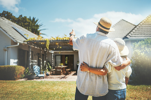 Back view, couple and pointing outdoor at new home, real estate or house investment. Man, woman and hug at front of property for moving together in building, dream neighborhood and mortgage at garden