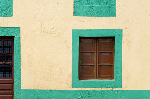 Window with white wooden shutters on wall building on the street in Singapore