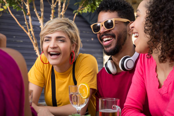 Cheerful young friends cheering and drinking together at cafe bar