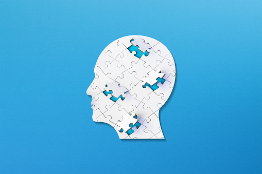 Brain shaped white jigsaw puzzle on colored background. Mental health and problems with memory.