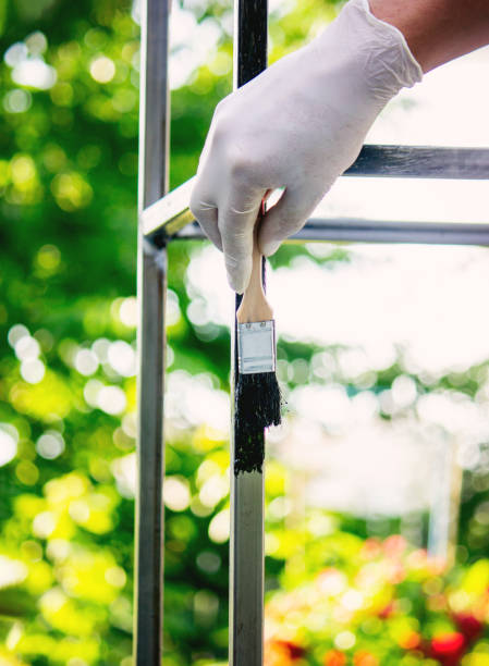 istock a man paints metal with black paint with a brush. 1769180332