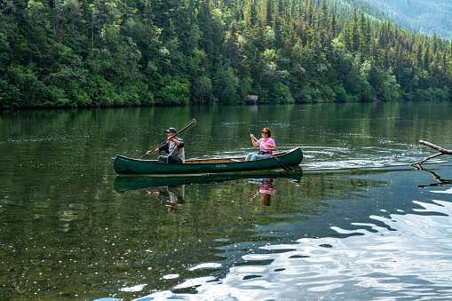 Family time, brother and sister learning to paddle canoe with father
