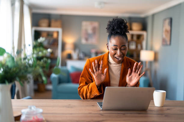 Kind smiling businesswoman waving hand looking at laptop during virtual video conference call in home office