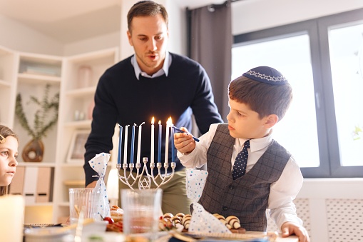 Cute little boy lighting Menorah with his father