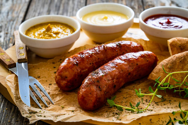 salchichas fritas y verduras en mesa de madera - sausage knackwurst food bratwurst fotografías e imágenes de stock