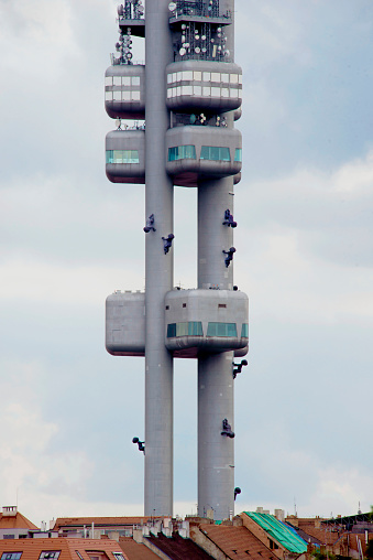 Prague, Czech Republic - 07/24/2024: The 709-foot transmitter Zizkov tower was built between 1985 and 1992 in the Zizkov area of Prague. Many residents felt that it was an ugly reminder of the Soviet regime. Artist David Cerny sculpted ten fiberglass babies to attach to the pillars in 2000 temporarily. In 2001, they were permanently attached. Removed only for cleaning and sculptural checks, problems were found, and they were reattached with duplicates in 2019. The tower with babies is now a tourist attraction.