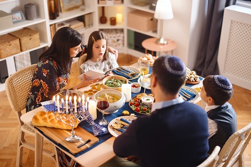 Jewish family sitting at the table and celebrating Hanukkah