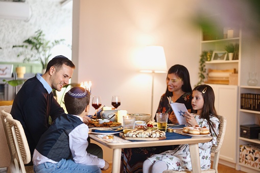 Little girl reading Hebrew bible at the dining table during traditional Hanukkah diner