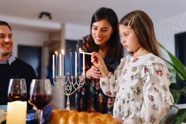 istock Cute girl lighting Menorah at the dining table 1769276289