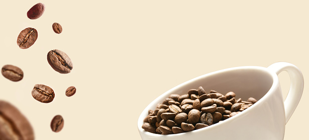 Coffee concepts. Coffee beans and coffee cup on colored background with copy space. Coffee beans in a coffee cup