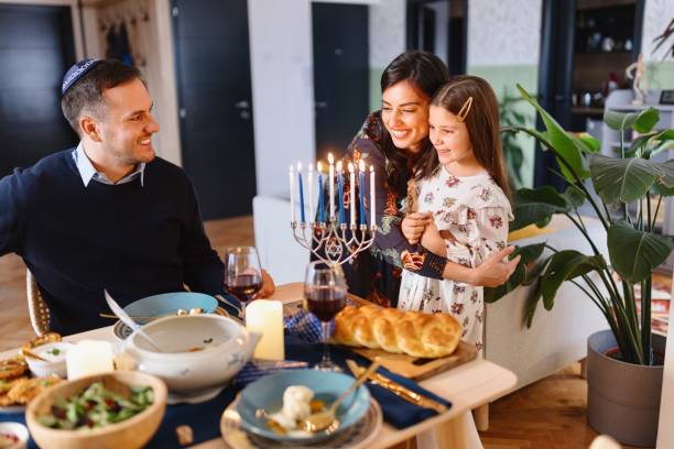 istock Jewish mother hugging her little daughter while lighting Menorah 1769277878